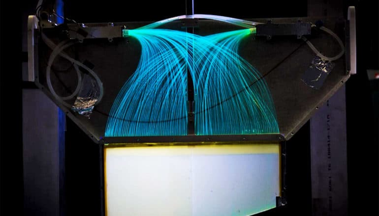 The ultracold neutron detector has many blue lines of light arcing into a main container