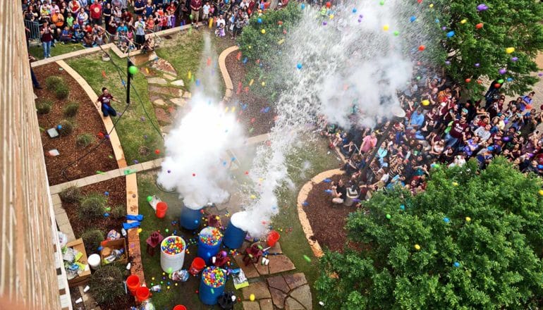 A crowd watches plastic barrels filled with water and plastic balls explode into the air