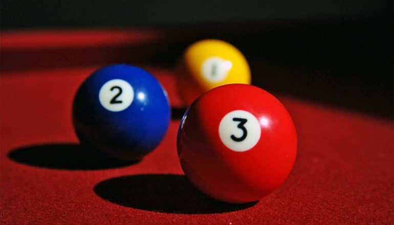A yellow, blue, and red billiard ball on a red table