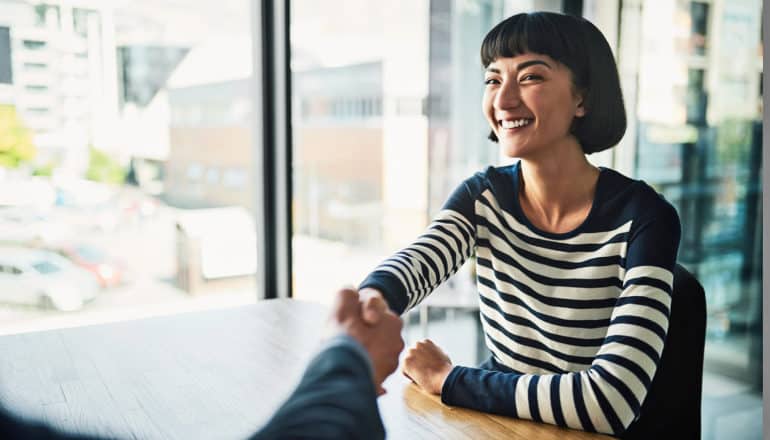 seated person smiles and shakes hand