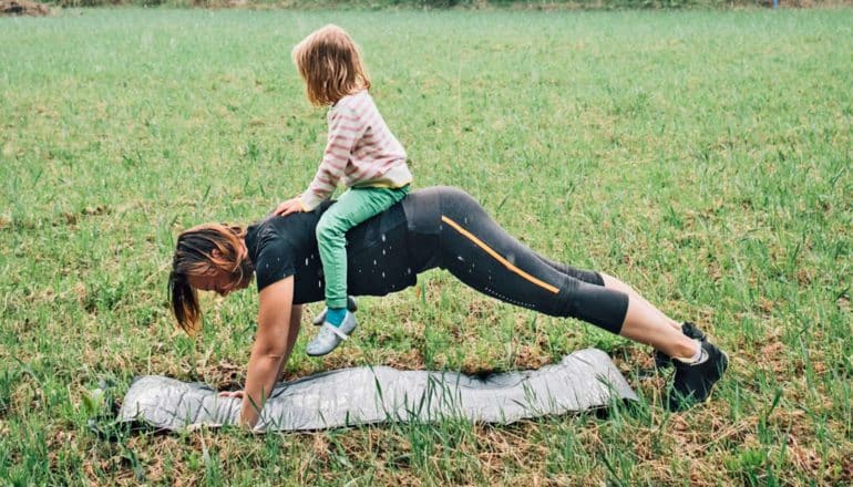 adult does push-up outdoors with child on back