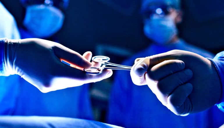 Two surgeons pass a scissors tool while in the operating room