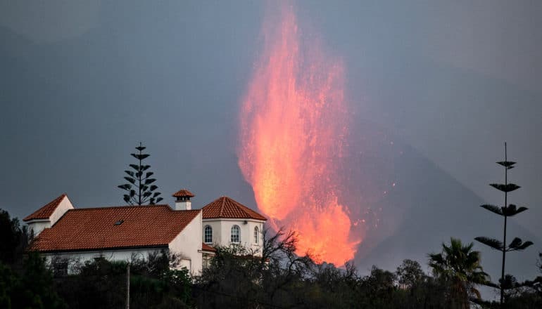 fiery plume behind trees and building