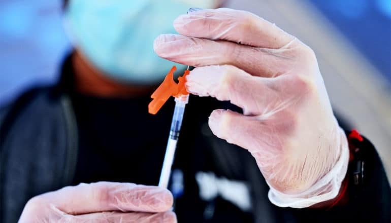 A health care worker fills a syringe with the COVID-19 vaccine