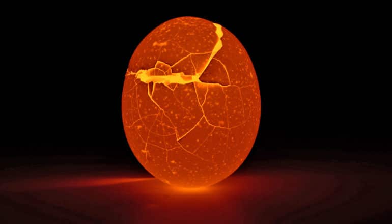 A cracked eggshell glows red against a black background