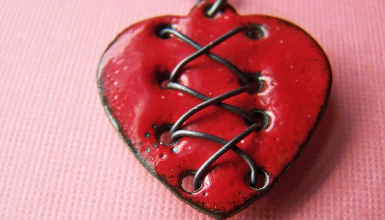 A ceramic heart with metal thread in stitching pattern woven through it