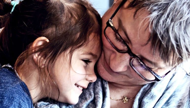 A grandmother cuddles her smiling grandaughter