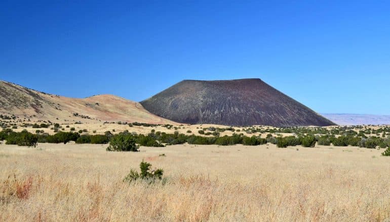 field in front of dark volcanic mound