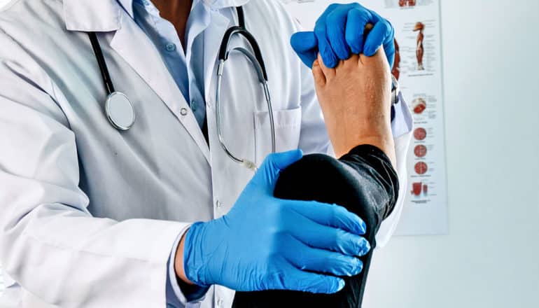 A doctor bends a patient's knee while supporting their leg