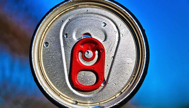 The top of a soda can with a red tab against a blue background