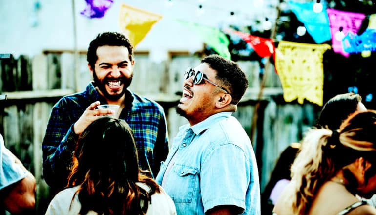 People talk and laugh while outside at a backyard party