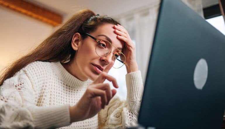 person looks weary in front of laptop