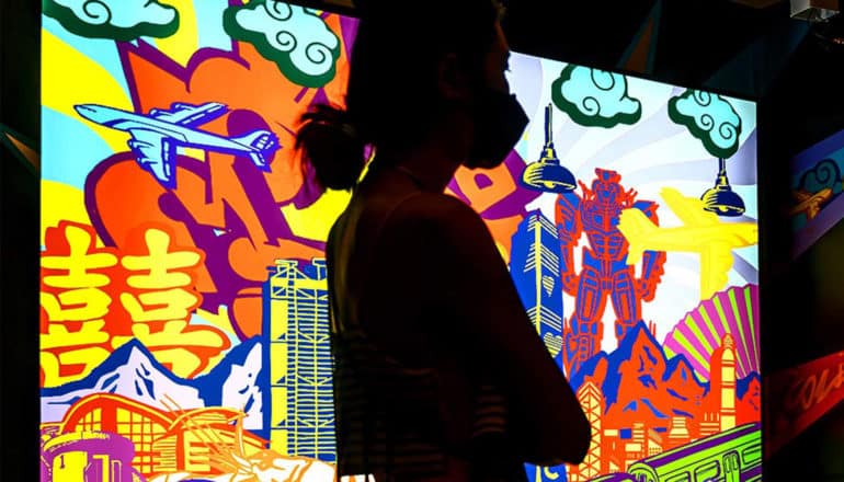 person in silhouette looks at colorful screens