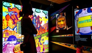 person in silhouette looks at colorful screens