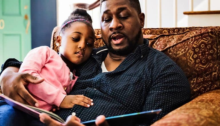 A father reads a book to his daughter