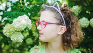 kid in neon glasses and cat headband smells hydrangea