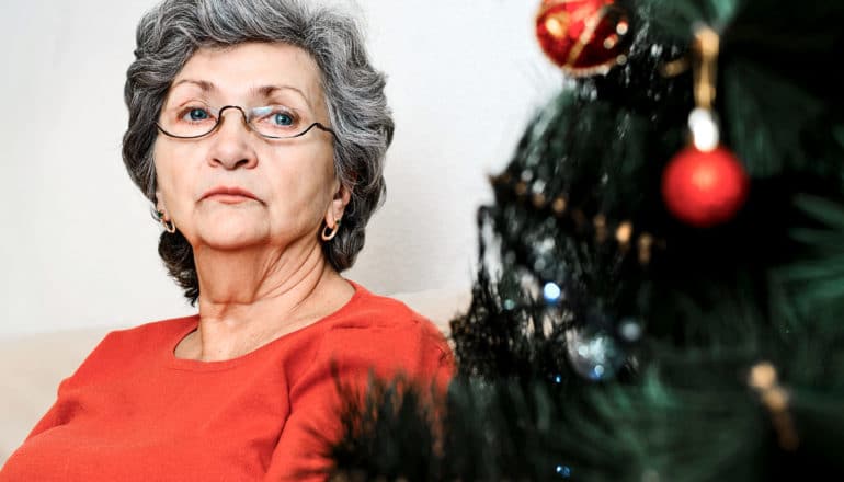 mature adults looks sadly at Christmas tree