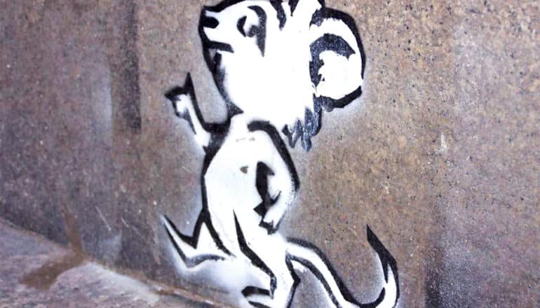 A stencil of a cartoon mouse walking on two legs printed on a wall