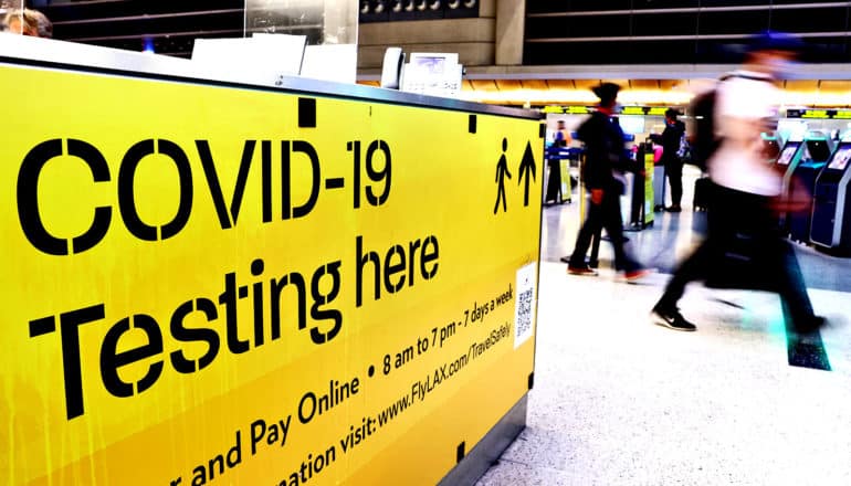 A sign in an airport directs travelers to COVID-19 testing