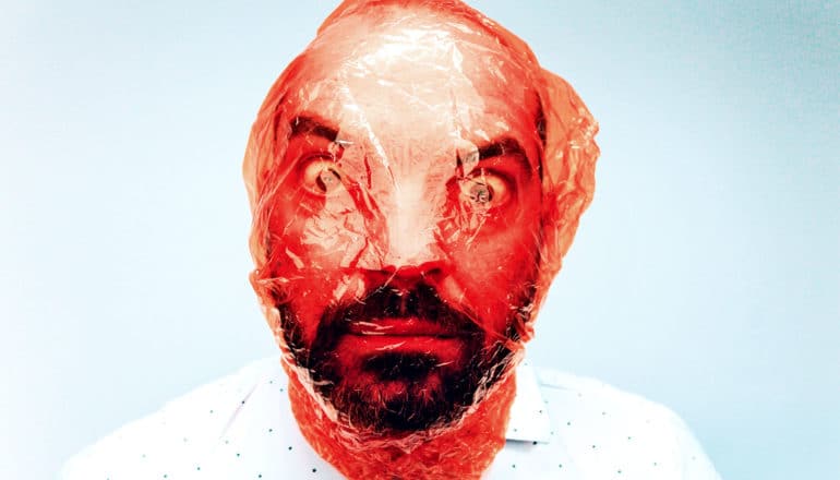 A worried man's face covered in red plastic