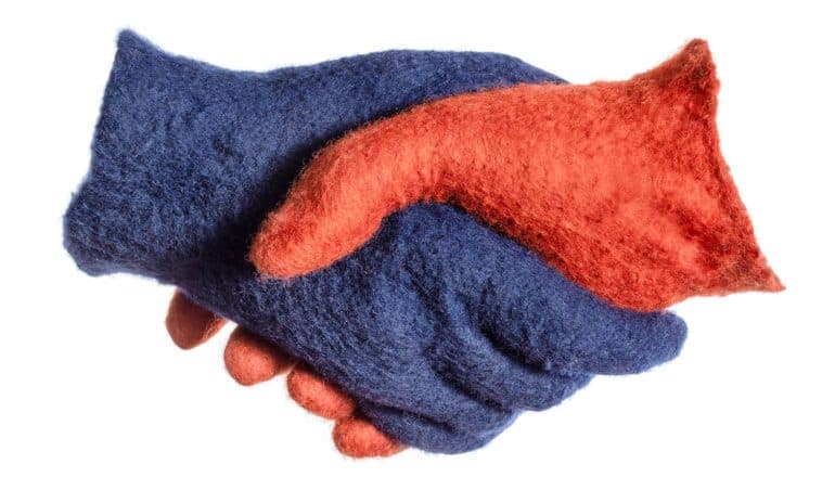 Two felt gloves, one red and one blue, shake hands on a white background