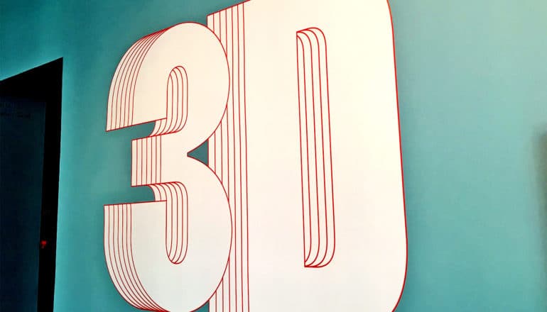 A blue wall has "3D" painted on it in letters that looks three dimensional