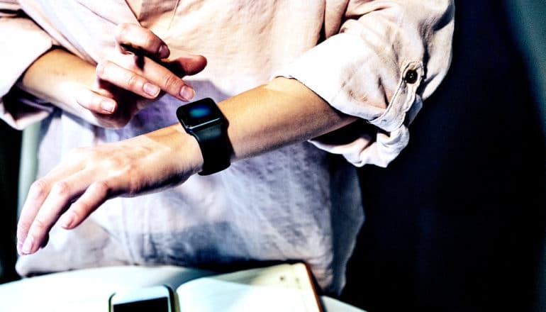 A woman touches her finger to her smartwatch