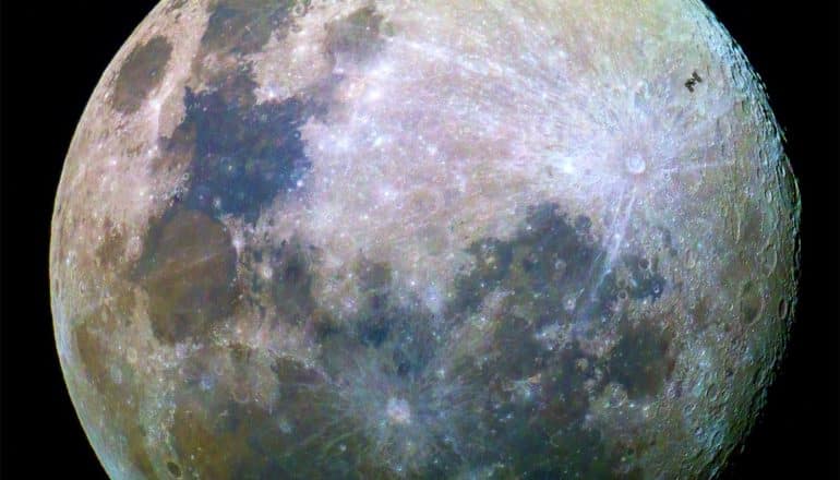 A close-up shot of the surface of the moon while the International Space Station passes over