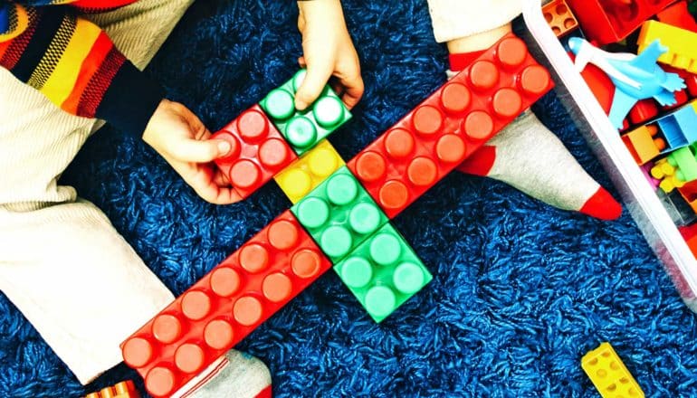 A young boy makes a plane from plastic building blocks