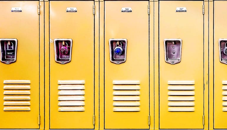 A row of yellow school lockers with padlocks on them