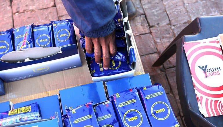 A young man reaches into a box of free condoms