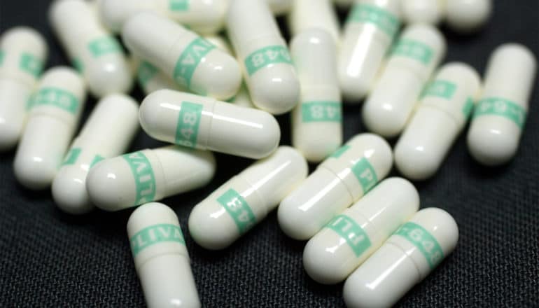 Many white and green capsules on a dark background