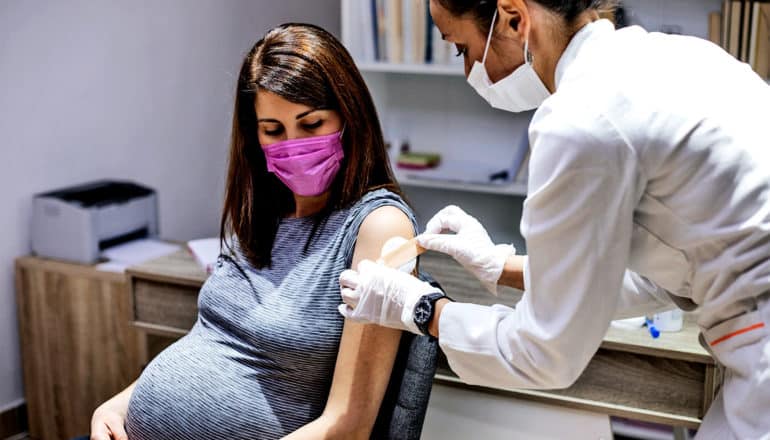 A doctor gives a pregnant woman a covid-19 vaccine