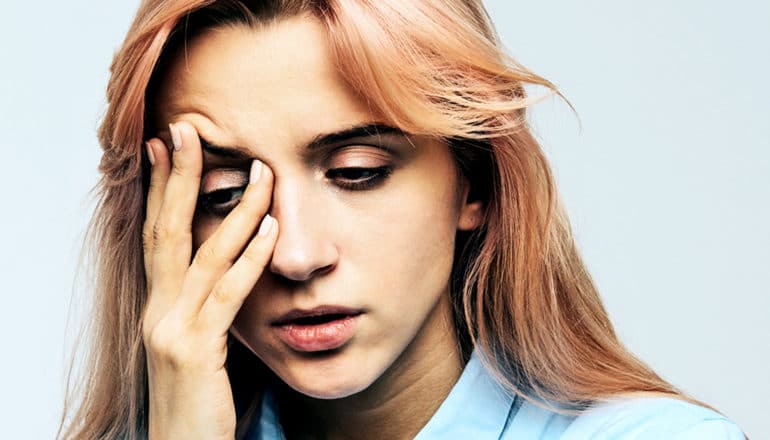 A young woman rubs her forehead