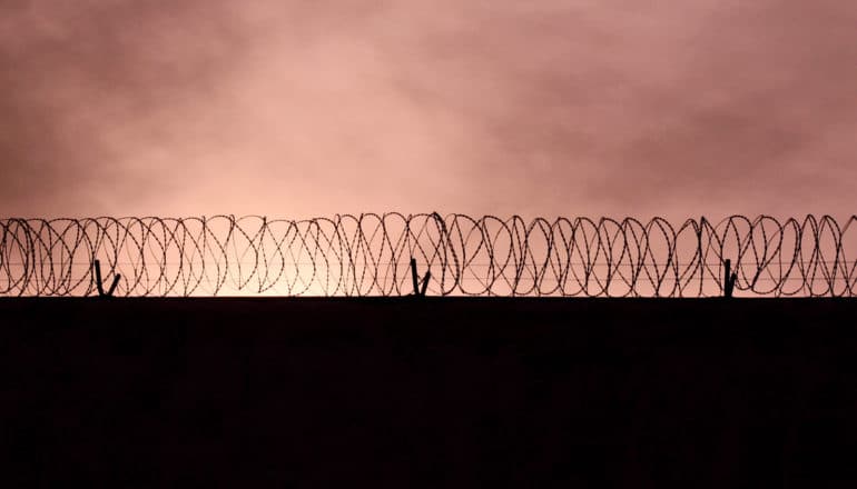 pinkish sunset over razor wire on wall