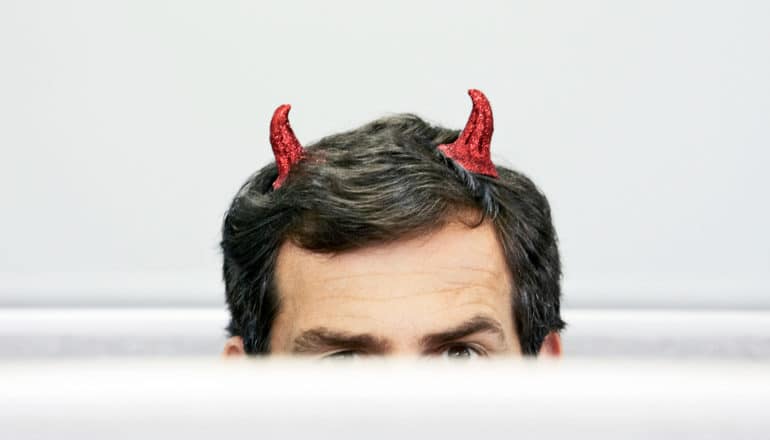 person in cubicle wears devil horns