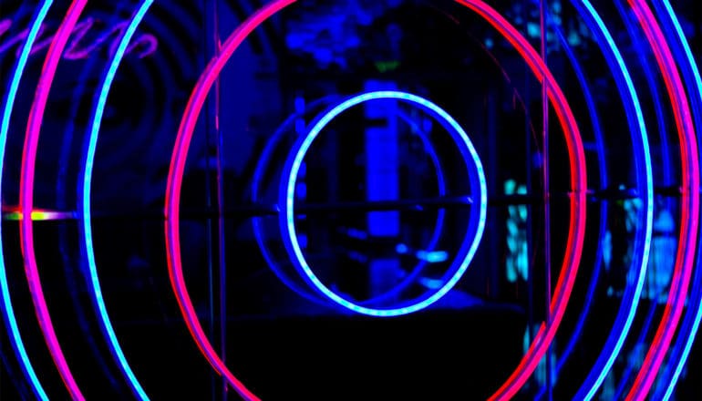 A neon sign has a blue and pink target design