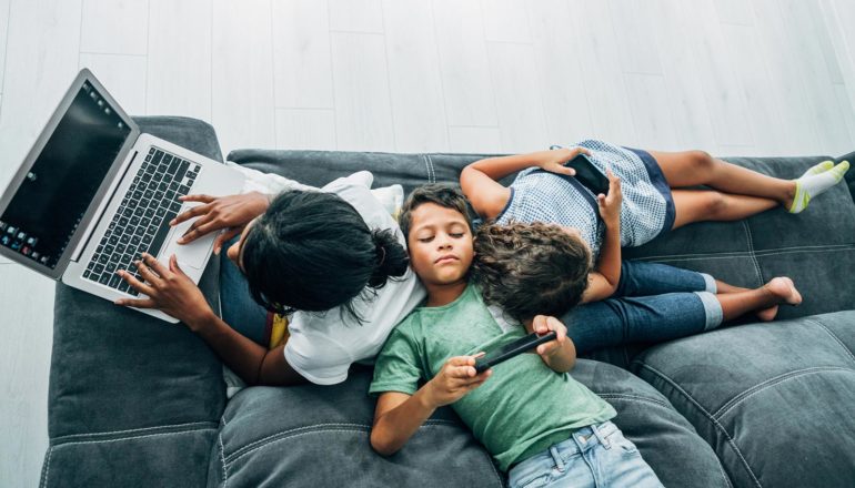 kids flop on adult using laptop on couch