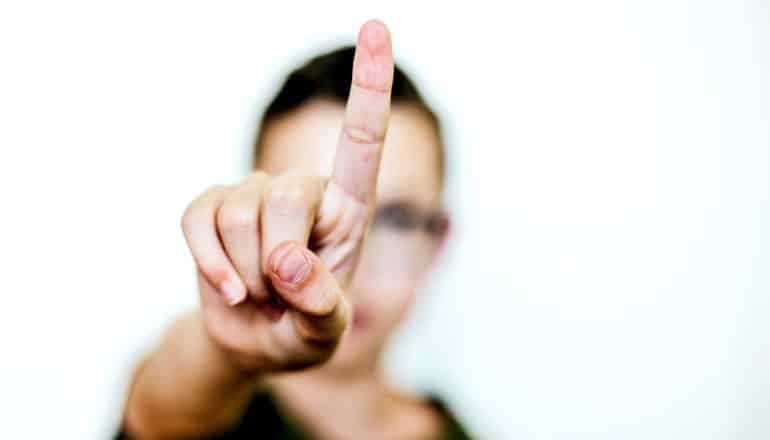 A young boy holds up his index finger