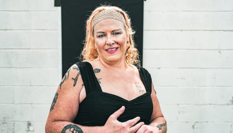 trans woman in headband and black top smiles