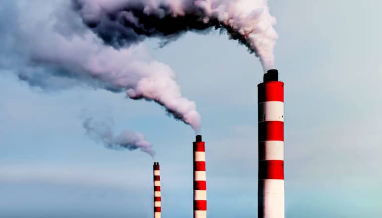 Smokestacks at a power plant pour smoke into the sky