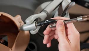 A person uses a surgical tool on the open head of a dummy