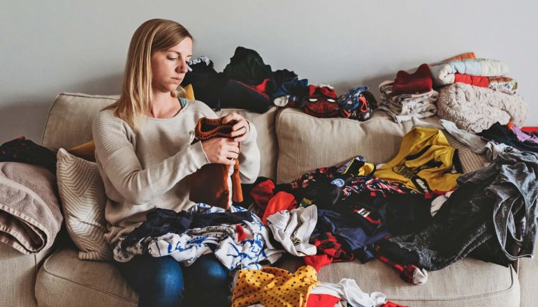 sad person folds laundry on couch