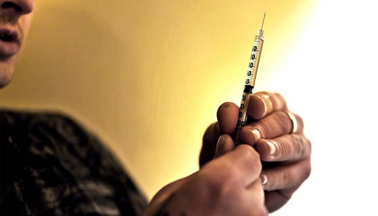 A man holds a syringe of heroin