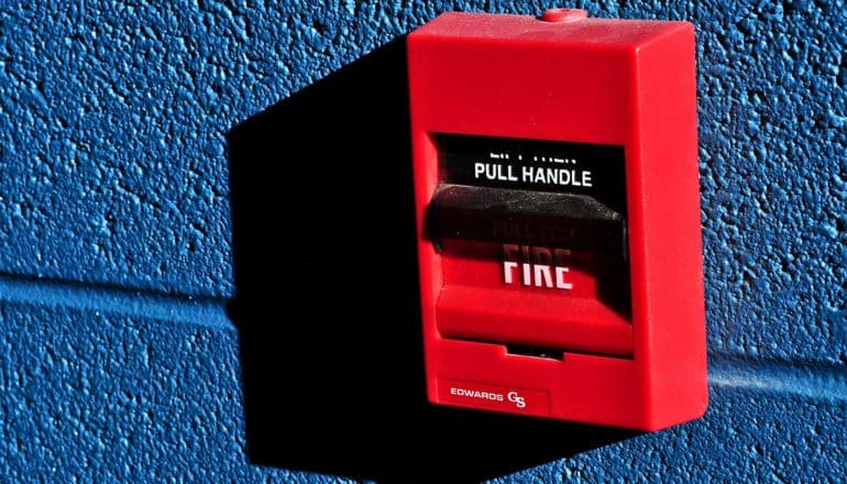 A red fire alarm box on a blue wall