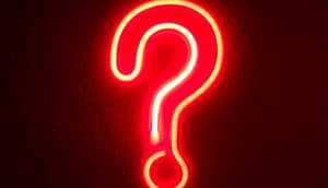 A red neon question mark against a dark background