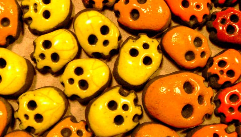 Small cookies decorated like orange, yellow, and red skulls