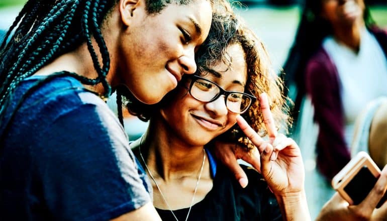 Two teen girls pose for a selfie while smiling