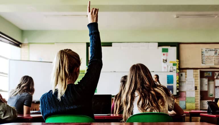 A high school student raises her hand in class