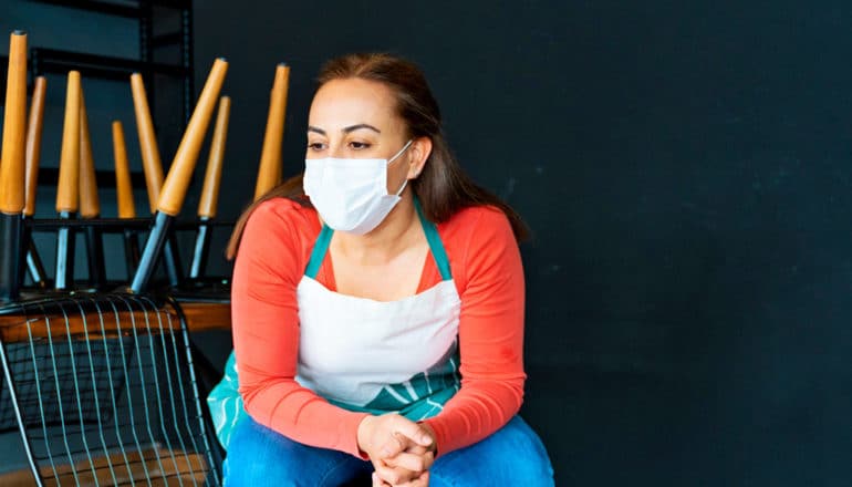 seated figure in mask and apron